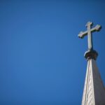 A cross on top of the steeple of a church.