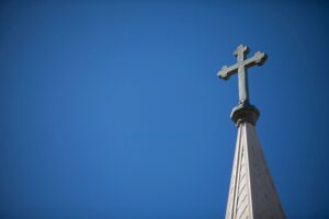 A cross on top of the steeple of a church.