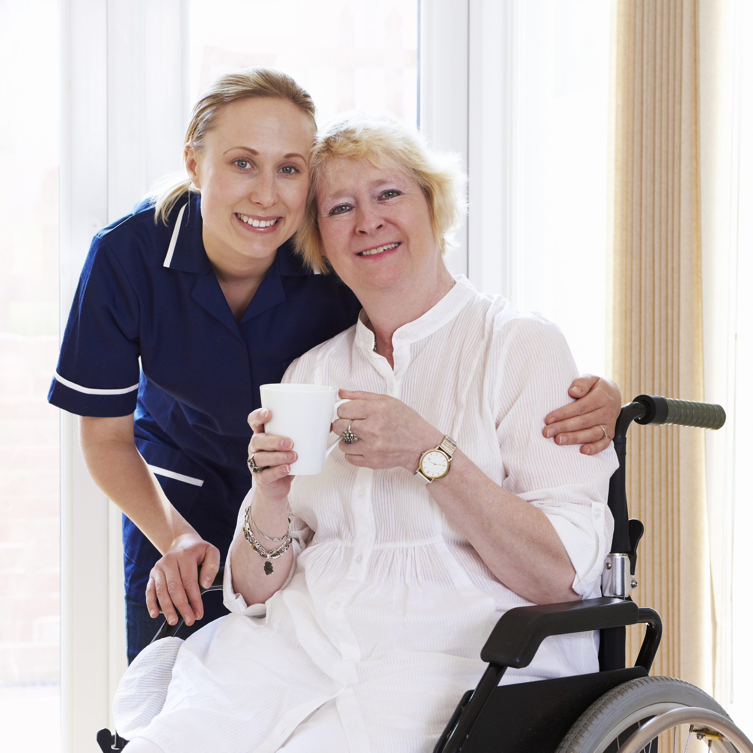 Smiling caregiver with elderly woman in wheelchair