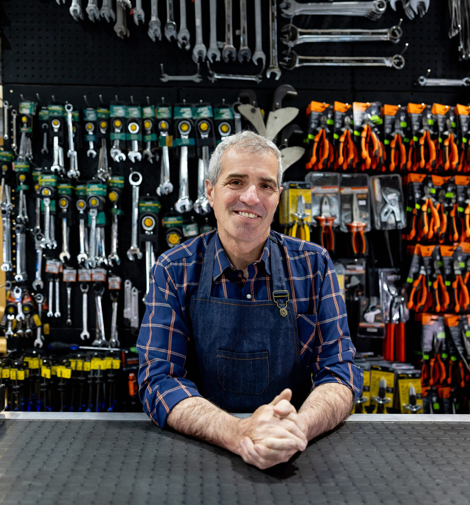 Smiling hardware store owner behind tool counter