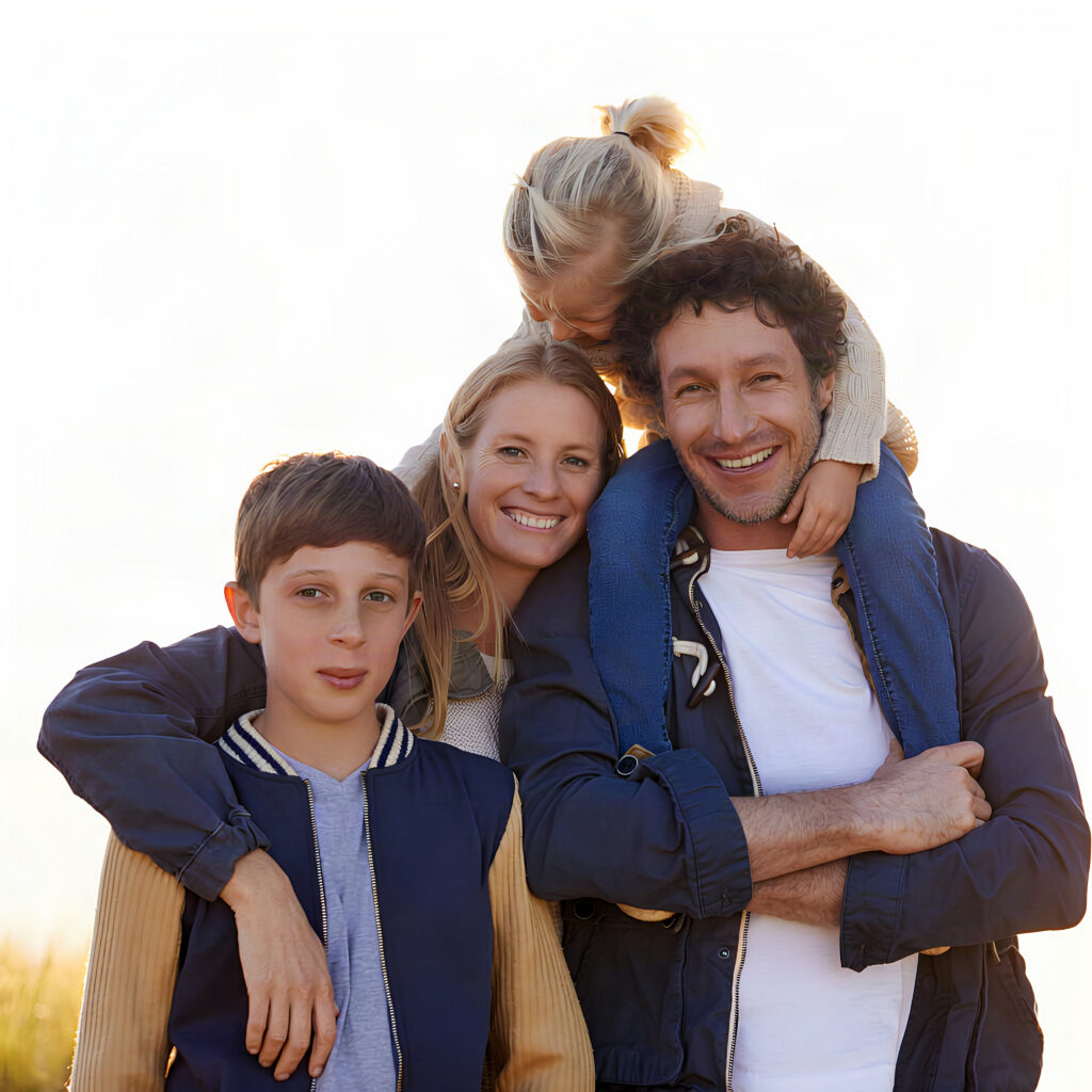 Smiling family of four outdoors at sunset